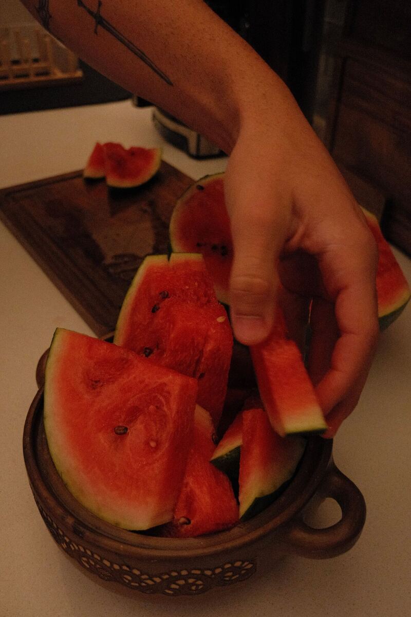 Hand reaching into a bowl of watermelon slices